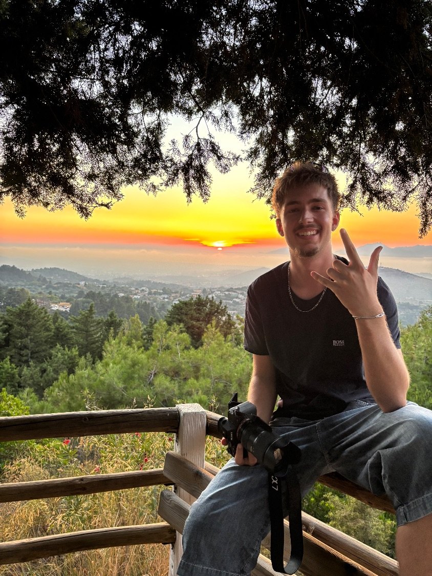 Yanis Lasne, appareil photo à la main, devant un coucher de soleil